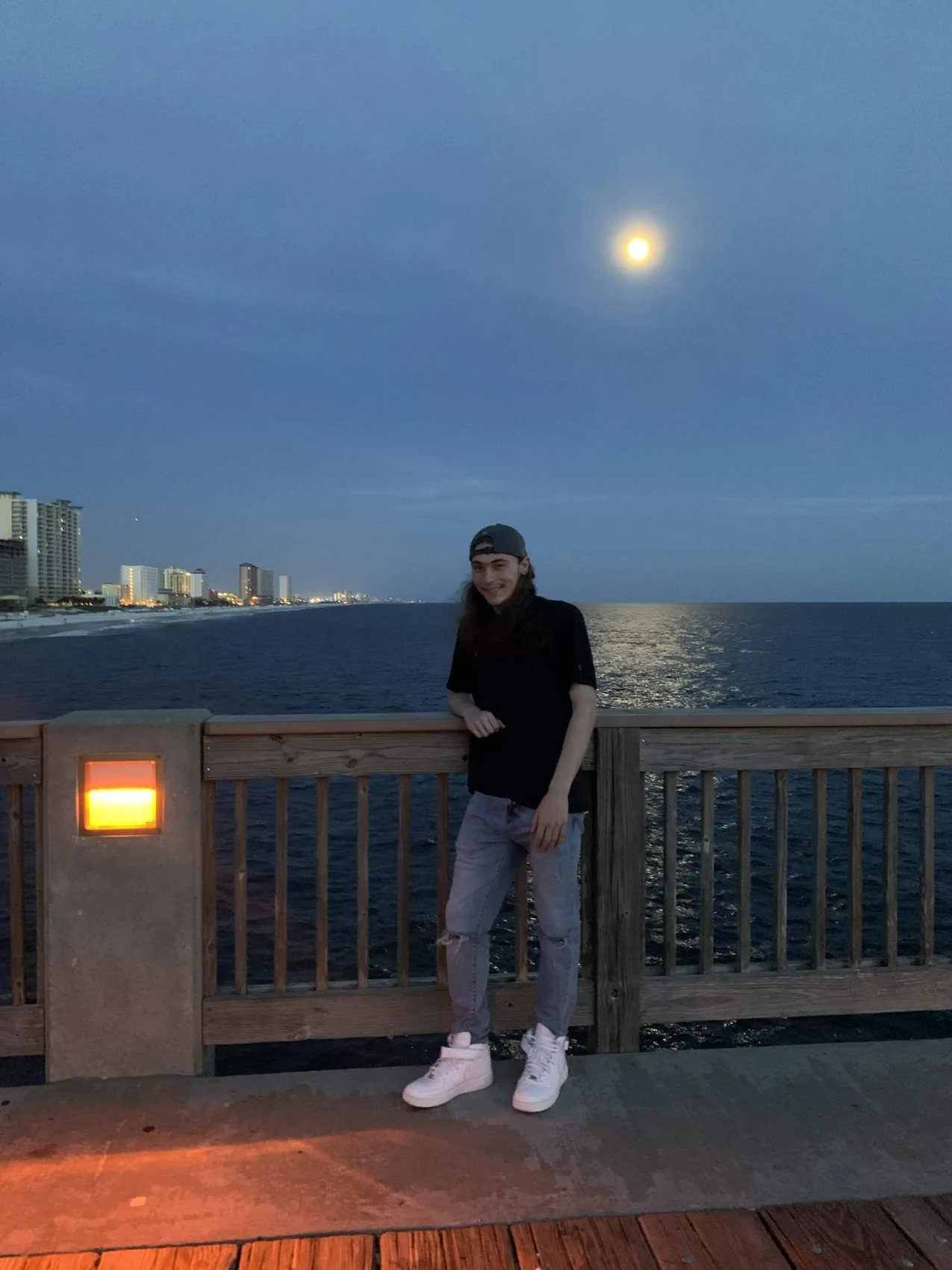 Shayne smiling by the water beneath the moon.
